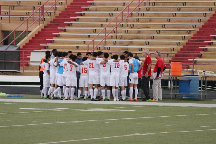 The varsity boys soccer team huddles up before their game against Friendswood.