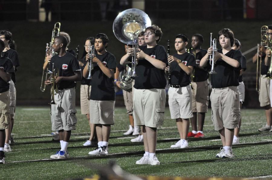 Junior Will Kennedy and other band members stand at attention during a halftime performance.