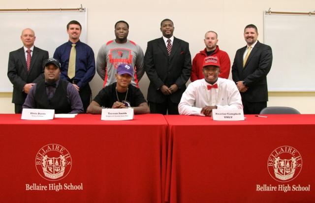 Varsity football players seniors (from left to right) Elvis Davis, Trevon Smith, and Xzaviar Campbell sit in front of their coaches and college representatives. 