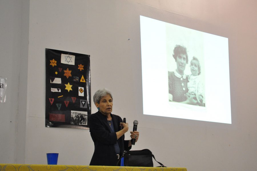 Holocaust Survivor gives presentation about her life. Behind her are articles from the Holocaust, such as the yellow Star of David.