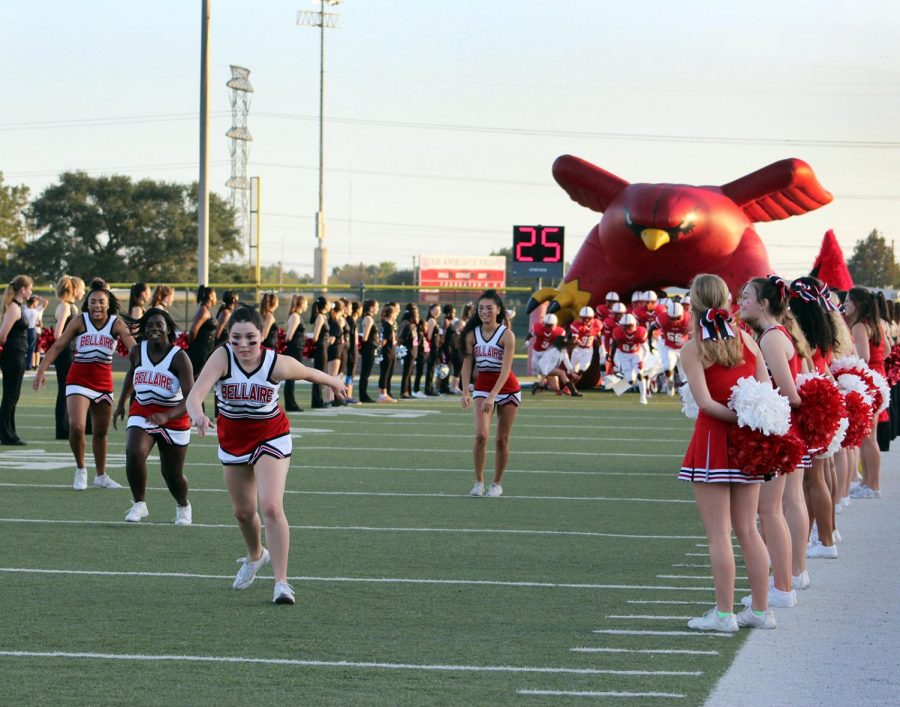 Cheerleaders barrel through the cardinal tunnel to introduce the football players.