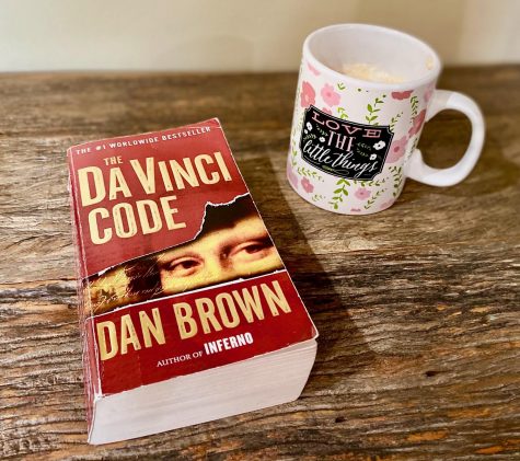 Taryn Morris reads The Da Vinci Code while drinking a cup of hot chocolate. Published in 2003 and having around 80 million sold copies, The Da Vinci Code is one of the best-selling books of all time.