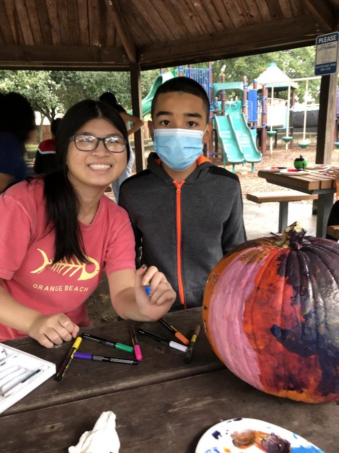 Junior Samantha Ho (right) and Lewis Coronado (left) decorate pumpkins with markers and paint. They chat about Scooby Doo while painting characters on their pumpkin.