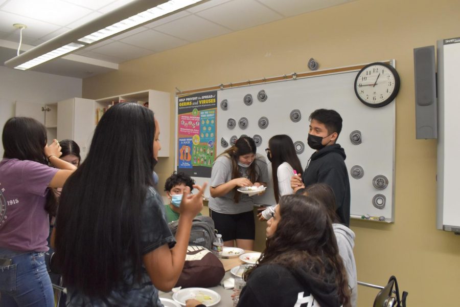 Students attend the Spanish Club meeting and talk over eating. They enjoy the foods and treats provided.