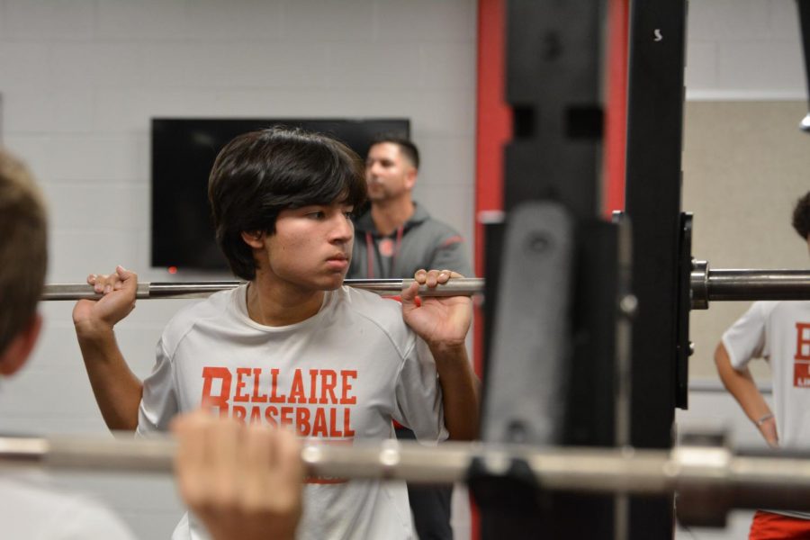 Senior Chris Jacinto, third baseman,  squats a 45 lb. bar for repetitions, training his leg muscles to be a stronger baseball player during the baseball teams weight session on Nov. 15.