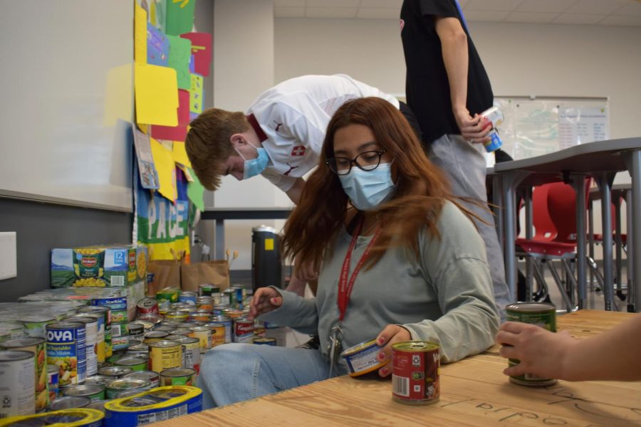 INHS president and senior Mackency Moreno sorts cans from the food drive at an INHS meeting during Cardinal Hour. Moreno said it was amazing to see how all of the teachers and students participated in the event.