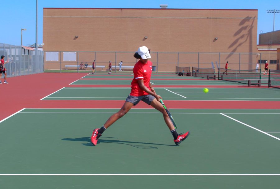 Sophomore Dhruv Balivada warms up at a Cy-Fair match. The varsity tennis player lunges for the ball and hits a forehand.