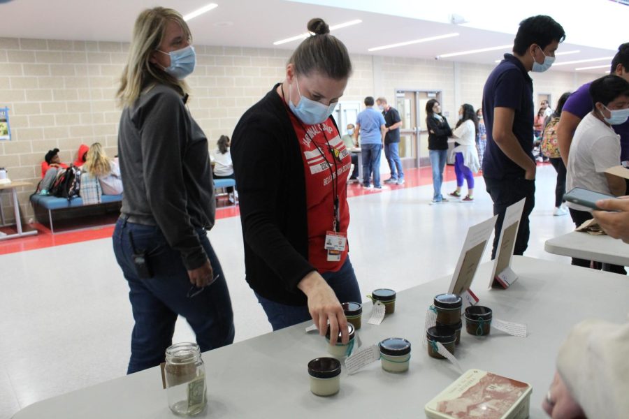AP World History teacher Jennifer Kuhleman carefully examines a jar of sea salt body scrub. Kuhleman ended up purchasing multiple scrubs and even promoted Cardinal Craft Clubs products to other friends and teachers.