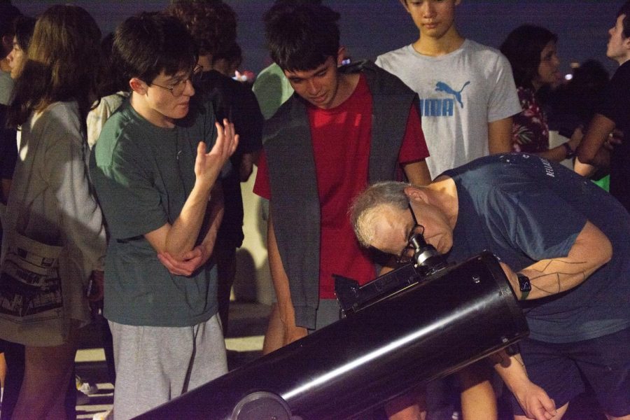 Club sponsor Jimmy Newland adjusts the telescope to aim at Jupiter as students wait in line for their turn.