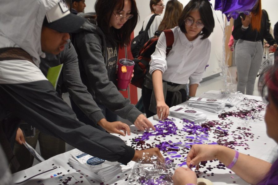 Students during lunch surround the domestic violence resource table set up by English teachers Jennifer Ho and Morgan Graham-Chilsom on the second floor near the stairwell. Ho and Graham took initiative to stir awareness among Cardinals on Oct. 20 for Go Purple Day.
