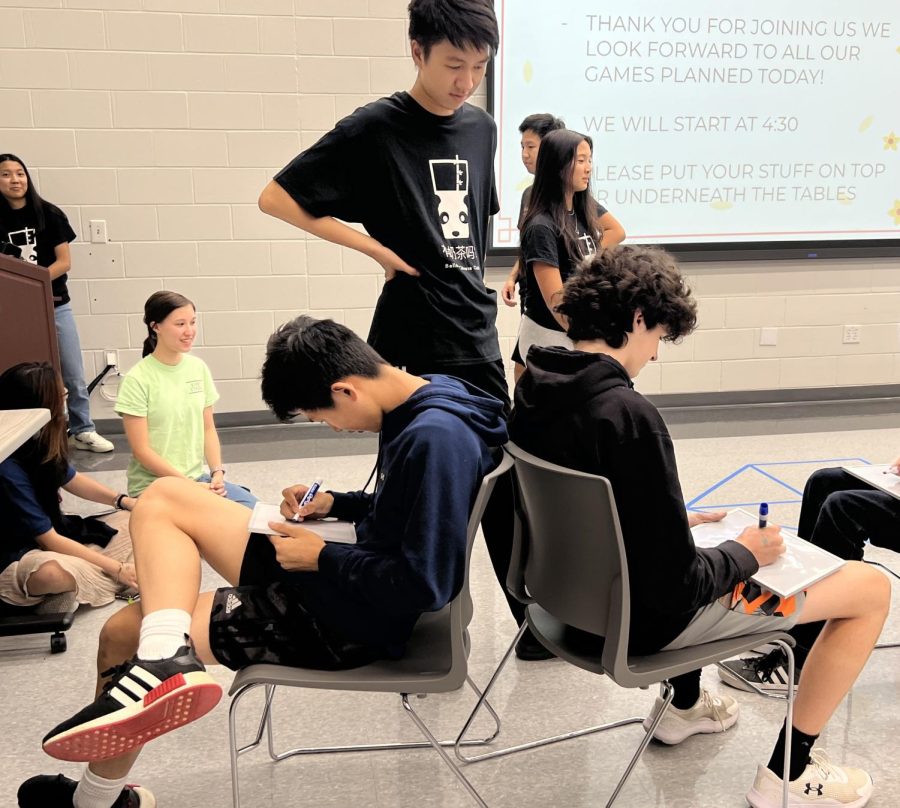 Freshmen Lucas Wang and Riley Hudlow write down their answers to a question in the friendship test on a white board while sitting back-to-back. Sophomore and tutorial manager Kevin Li stood behind them to prevent cheating and to keep track of their points.