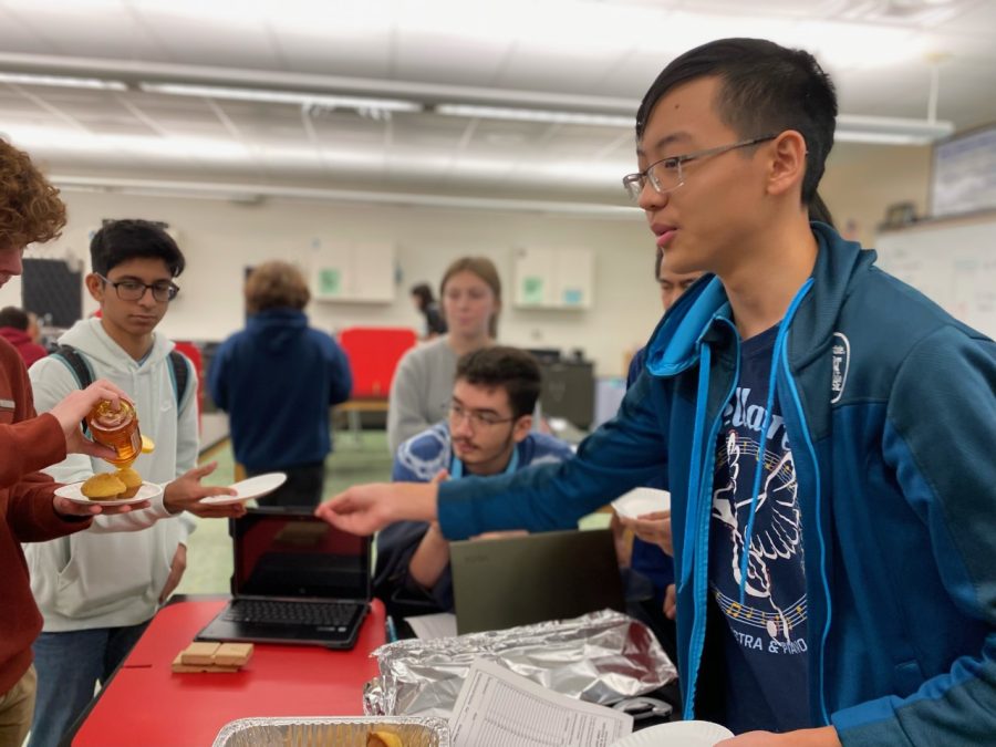 Vice President Caleb Chiao helps pass out plates with other officers to Bread Club members so they can take cornbread and drizzle honey on top. Sophomore Charlie Yu says that the bread is what he looks forward to every meeting.