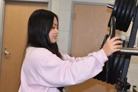 Sophomore Chloe Thepsouvanh on Sept, 22 takes a 25-pound weight from a weight holder in Bellaires weight room. Preparing to lift 95 pounds on the bench press for an after school workout.