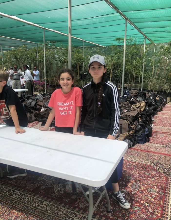 Hakki (right) stands at a table, working at a volunteer opportunity. Giving back to the community was very important in Aramco, and it is a value Hakki has carried with her.