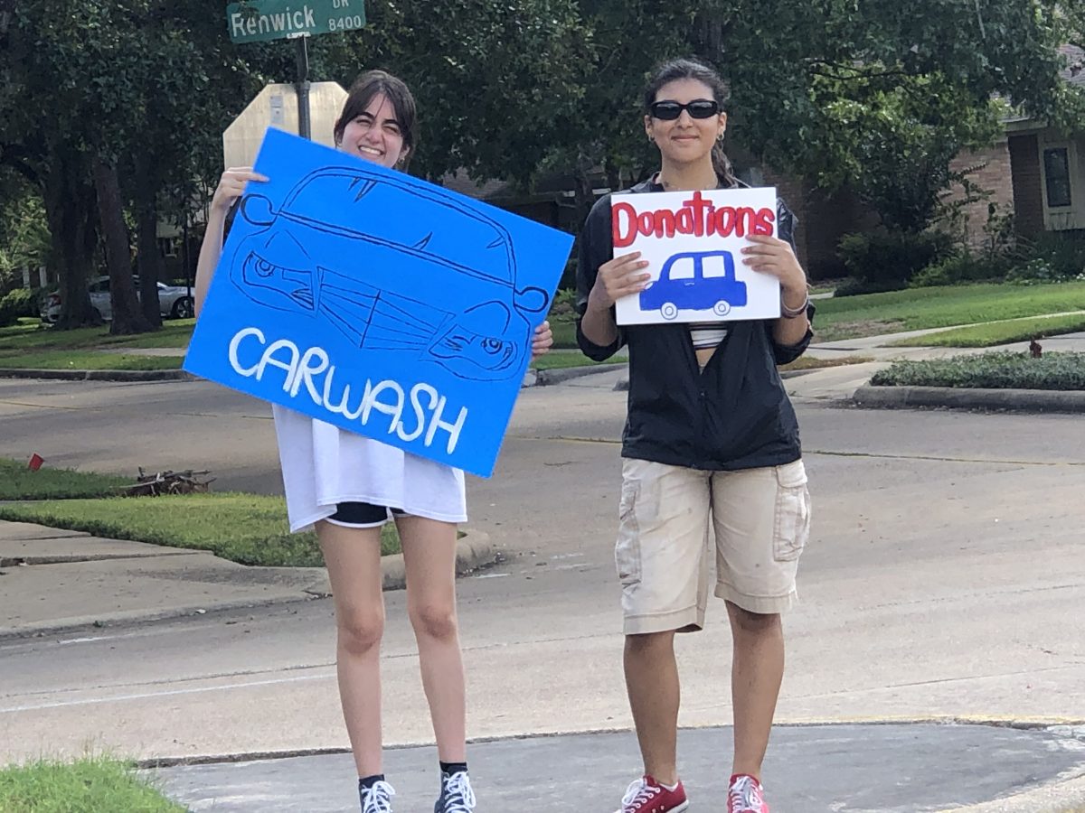 Seniors and vice presidents Kelly Garza and Ashlee Nunez advertise Rooftop Gardens car wash to nearby drivers. The club raised $300 from this fundraiser.