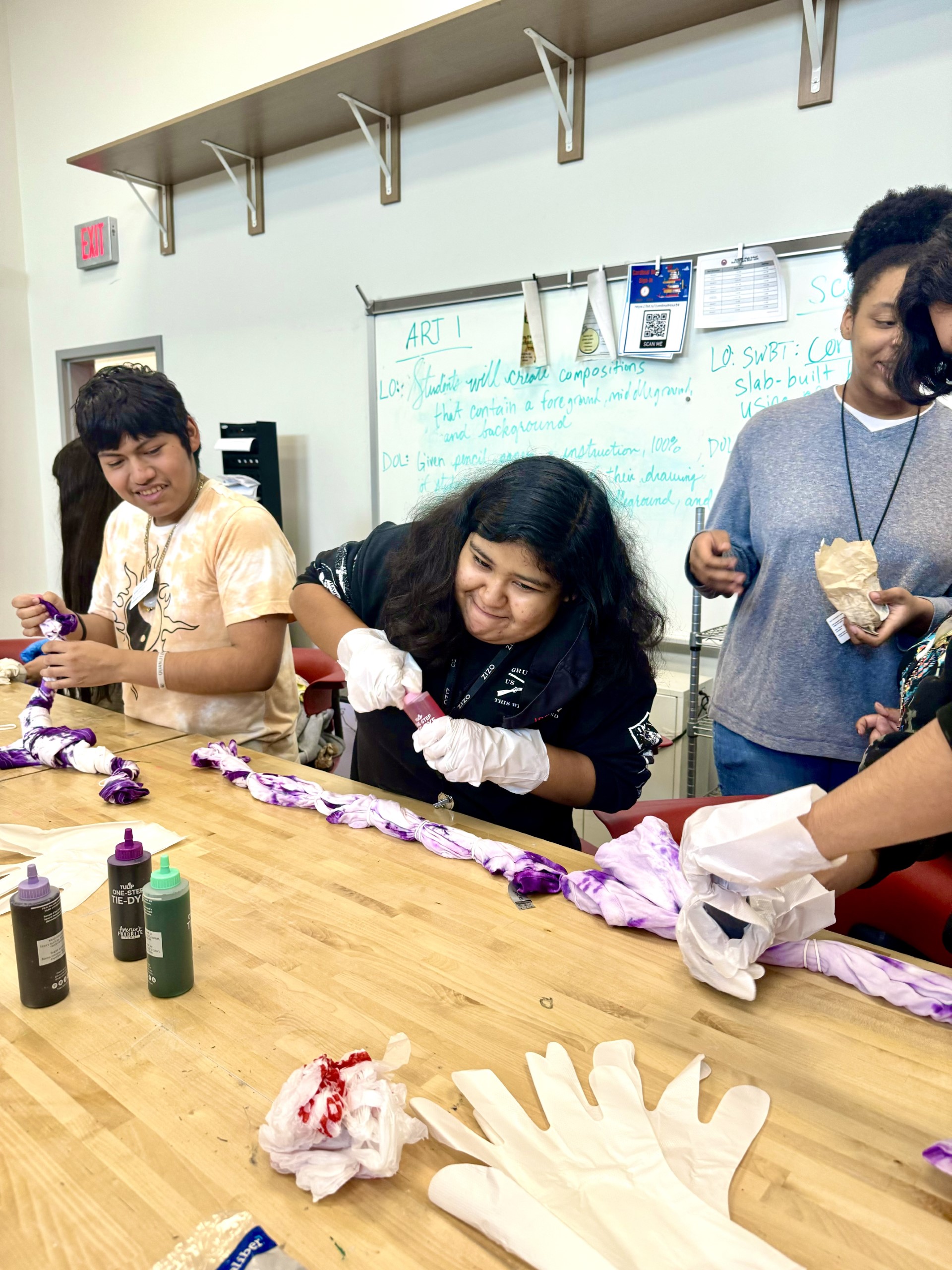 Sophomore Angle Ponce and Junior Iris BolanosGarcia select dyes to create multi-colored shirts. Club members used rubber ties to create rainbow spiral and crumple patterns.