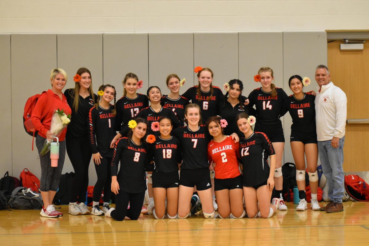 The Lady Cardinals JV team pose for a picture with their coaches, having flowers in their hair and tears in their eyes.