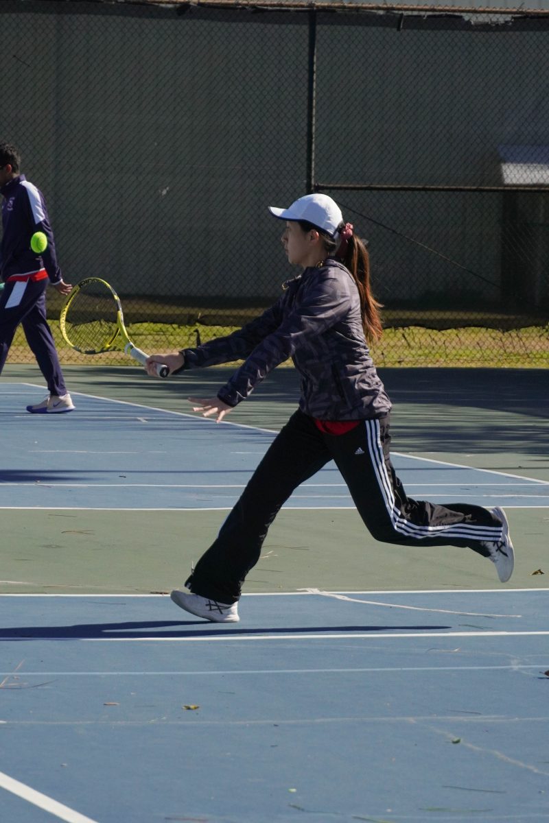 Ellen Dai runs to return a short ball during her girls doubles match. Dai plays on the outdoor courts of Chancellors Family Center.