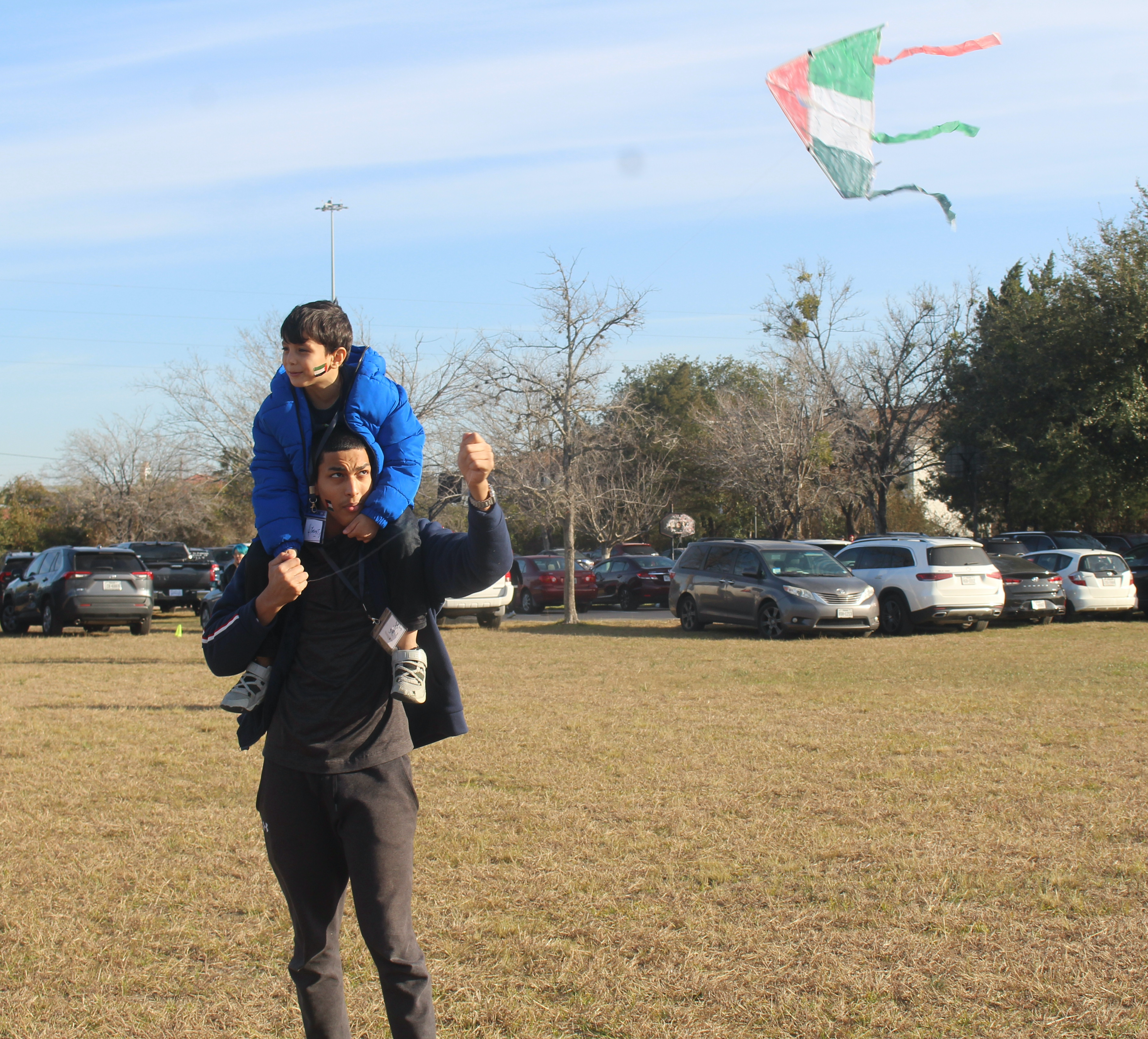 Junior Yousef Salem flies a kite decorated with the colors of the Palestinian flag with his younger brother Younis, who is in first grade, on his shoulders. In Refaat Alareers poem If I Must Die, kites are a symbol of hope for Palestinian children.
