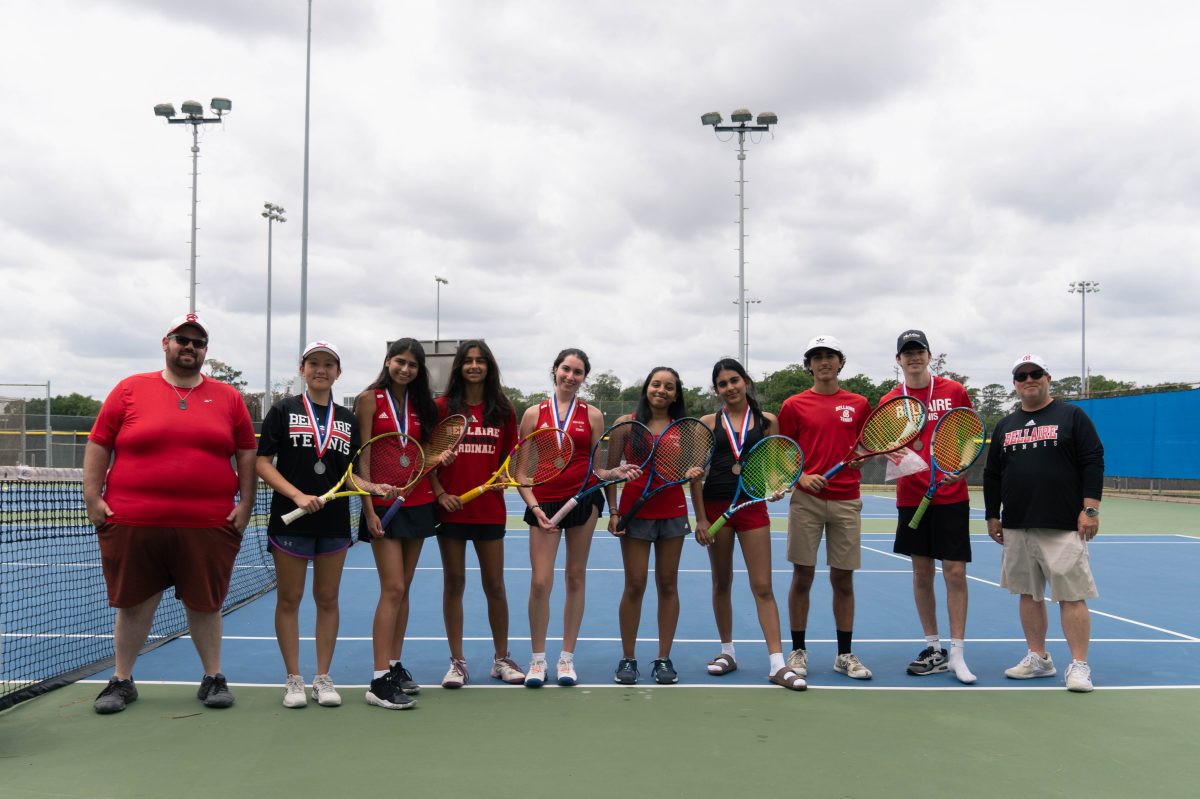 After nine hours of competition, the varsity district squad stands together with their rackets. Varsity coach Anthony Kirk, far right, and Junior Varsity coach Alex Brown, far left, accompanied the team during their matches throughout the day.