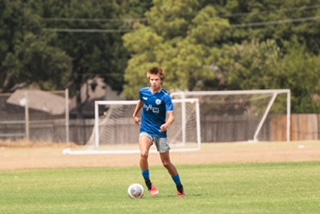 Junior Kai Nelson dribbles the ball down the field. This summer, Nelson participated in the IMG soccer camp.