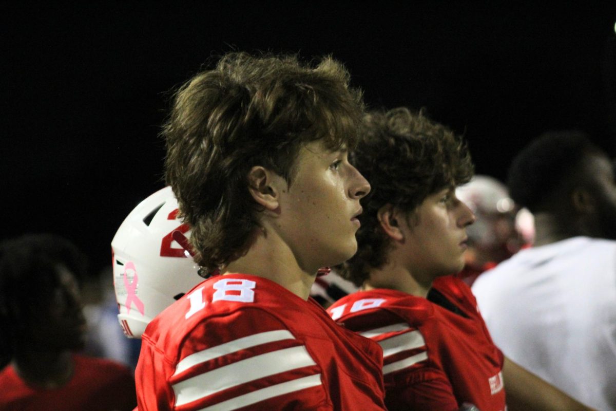 Junior defensive back Raymond Wohadlo and junior kicker Cole Mclean watch their team from the sidelines. Raymond is waiting to return back onto the field while Cole is on the sideline due to an injury.