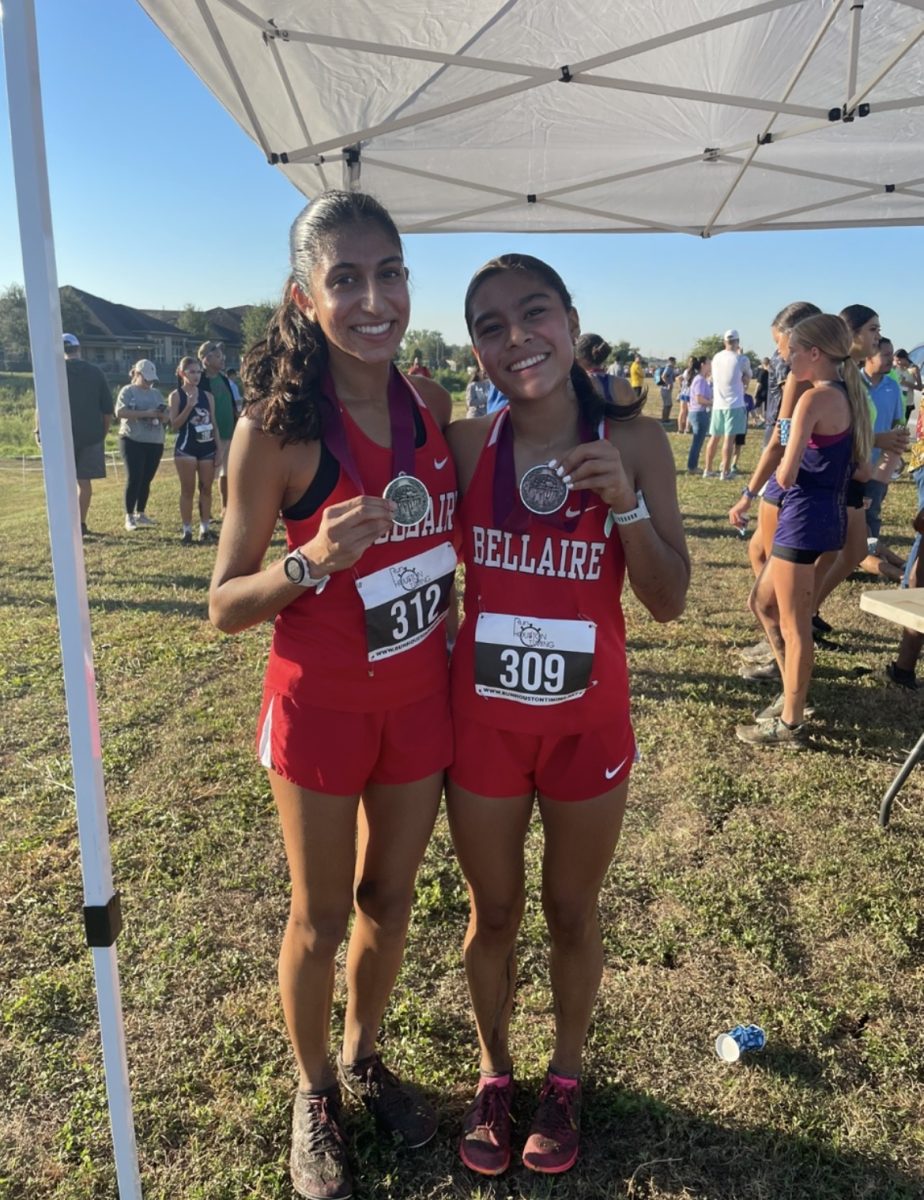 Sophomore Elizabeth Gamero holds up her medal alongside junior Sophia Hamdani after completing a cross country race. Gamero ran a total of 3.1 miles.