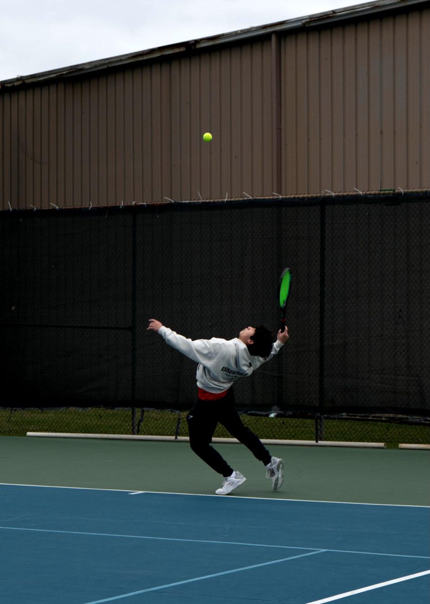 Junior Dylan Tran gazes toward the sky as he begins to swing at the ball during his serve. This was Tran's second match in the B boys' singles draw.