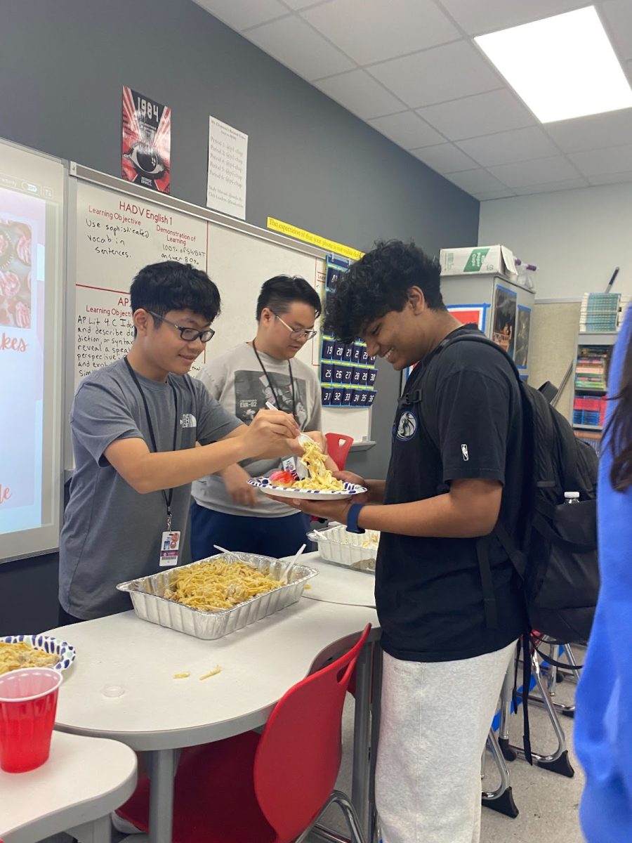 Sophomore and treasurer Grayson Yen-Asprec scoops chicken alfredo onto sophomore Abhineil Gotur’s plate. Yen-Asprec prepared the alfredo himself using high-quality ingredients.