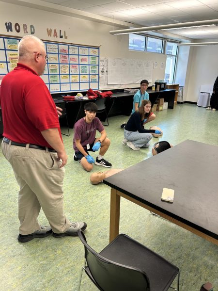 CPR instructor, James Browning, guides students preforming 30 timed chest compressions during quick emergency response training.