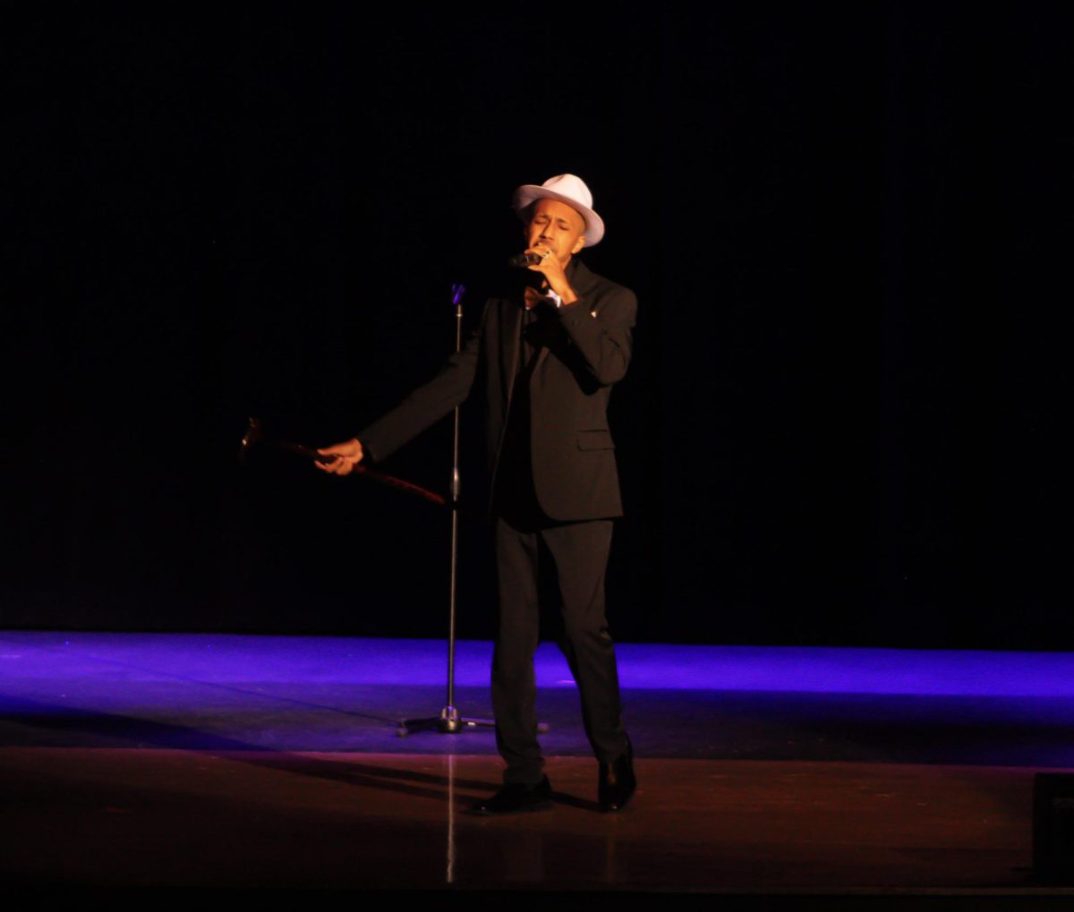 Senior Soleiman Barrera-Kelly holds a cane out while singing "Feeling Good" by Michael Bublé for his talent during Act VII. Barrera-Kelly is a member of varsity choir and theatre.