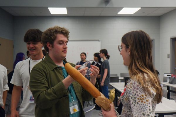 Bread Club President and senior Sam Dove helps a combatant put on safety goggles. Students participating in the fencing tournament had to sign a waiver and wear eye protection before fighting.