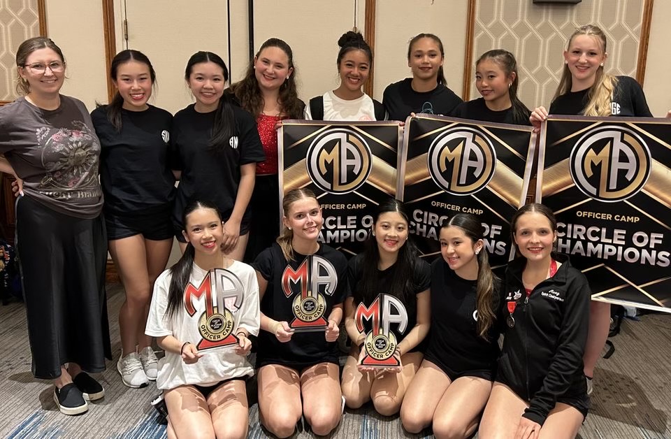 Senior and Belles president Chloe Lin shows other officers some of the many awards the Belles dance team has won. Lin directs the leadership training portion of the officer camp each June.