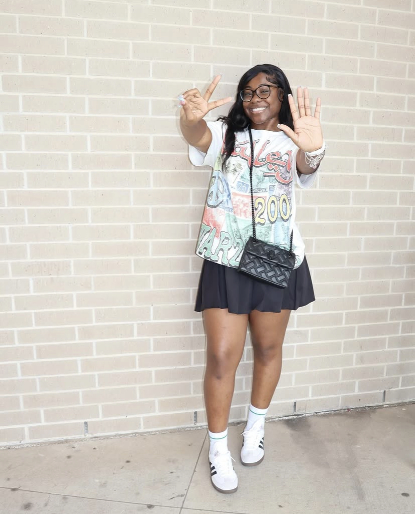 Senior Jada Johnson throws up a peace sign in front of a brick wall. She will attend Texas Southern University to major in Business Marketing.