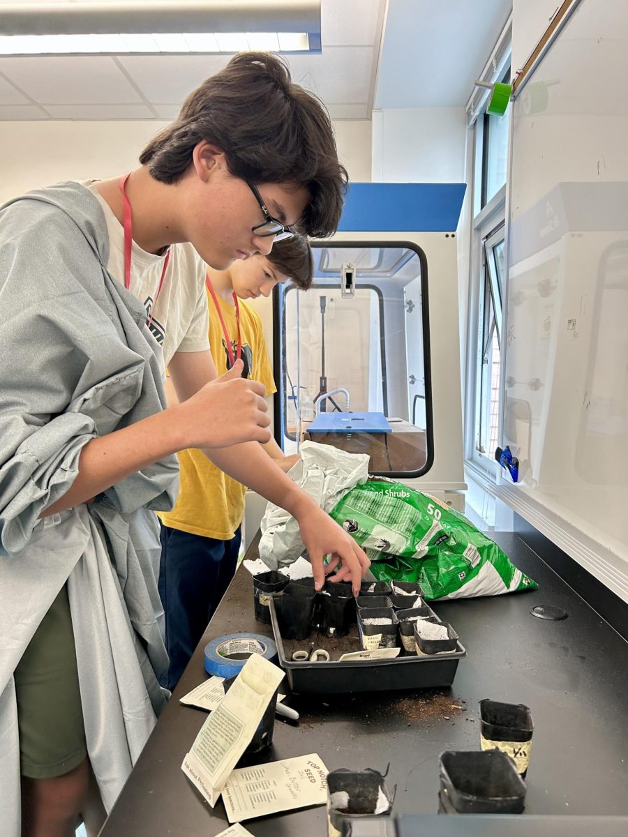 Sophomore Colin Jensen places his pot in a box with other club members’, as fellow sophomore Luca Hurtado-Borsa scoops soil into his pot. All gardening supplies and snacks were provided by the club officers. 