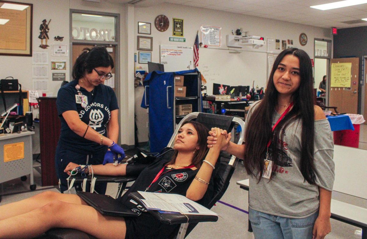 Senior Kimberly Garcia holds senior Leyla Vazquez's hand as she donates blood for the blood drive on Sept. 19. Garcia later donated plasma to the blood drive herself.