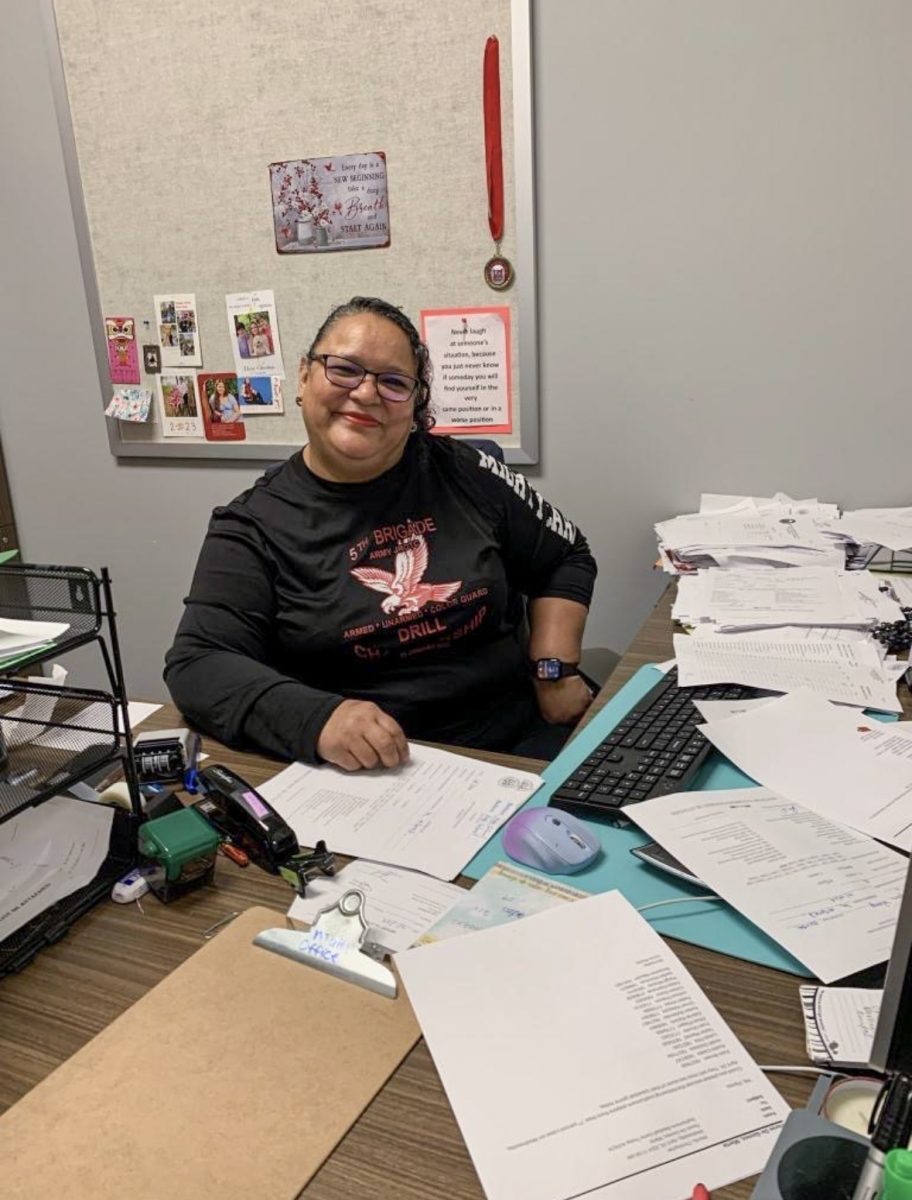 Flores smiles behind her desk in her office at school. Flores often has a lot of work to do during the school day, managing more than just attendance records.