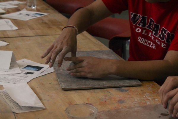 A student shapes clay to form the gourd shape of a pumpkin. Members learned how to put together pinch pots and smooth the seam to create their pumpkins.