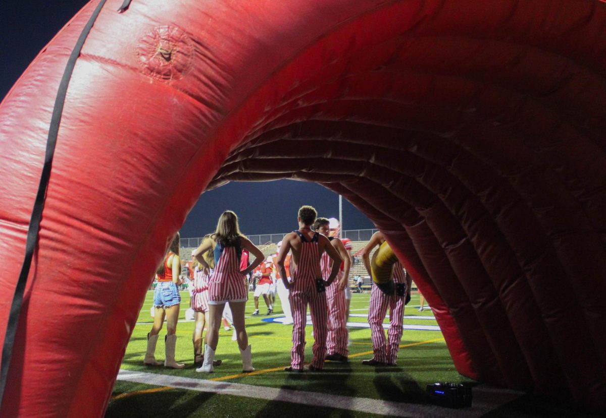 The Birdkeepers and Boosters stand inside the inflatable cardinal in preparation to welcome back the varsity football team after halftime. The theme of the game was U.S.A. and more than 100 students attended.