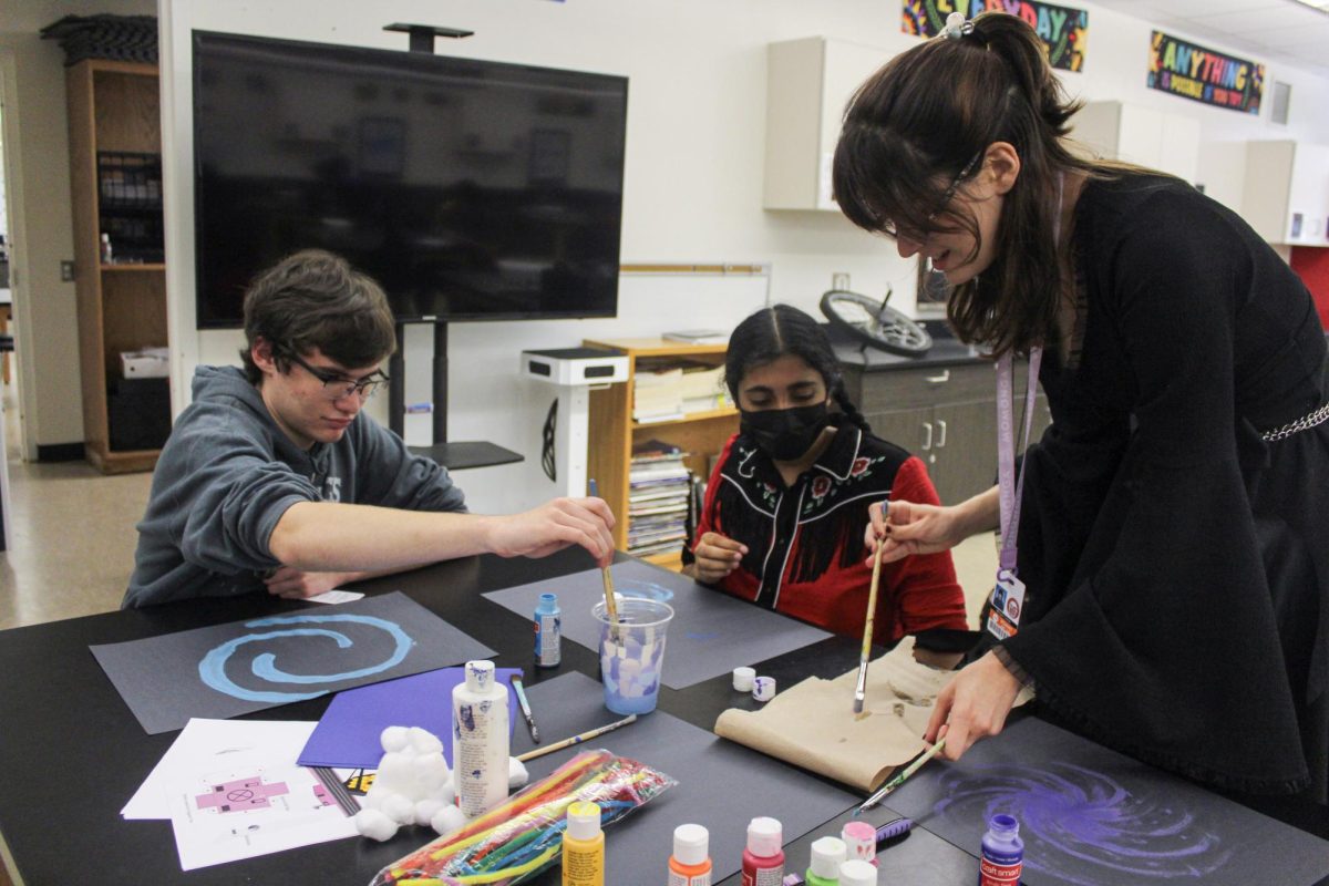 Sophomore Thurmond Johnson, senior Sara Kannan and senior Morgan Cremer paint their own galaxies. Craft supplies such as construction paper, paint and paint brushes were provided by Kannan. 