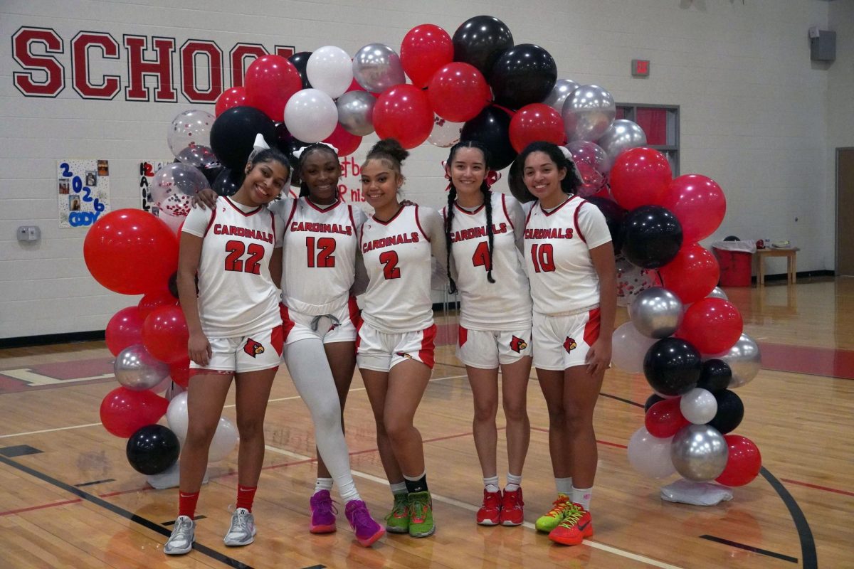 Seniors Cody Robinson, Lauren Burns, Hailey Brown, Indiana Pak and Ava Gusman pose for a pregame photo before senior night activities. The team managers, coaches and parents help set up decorations in the gym.