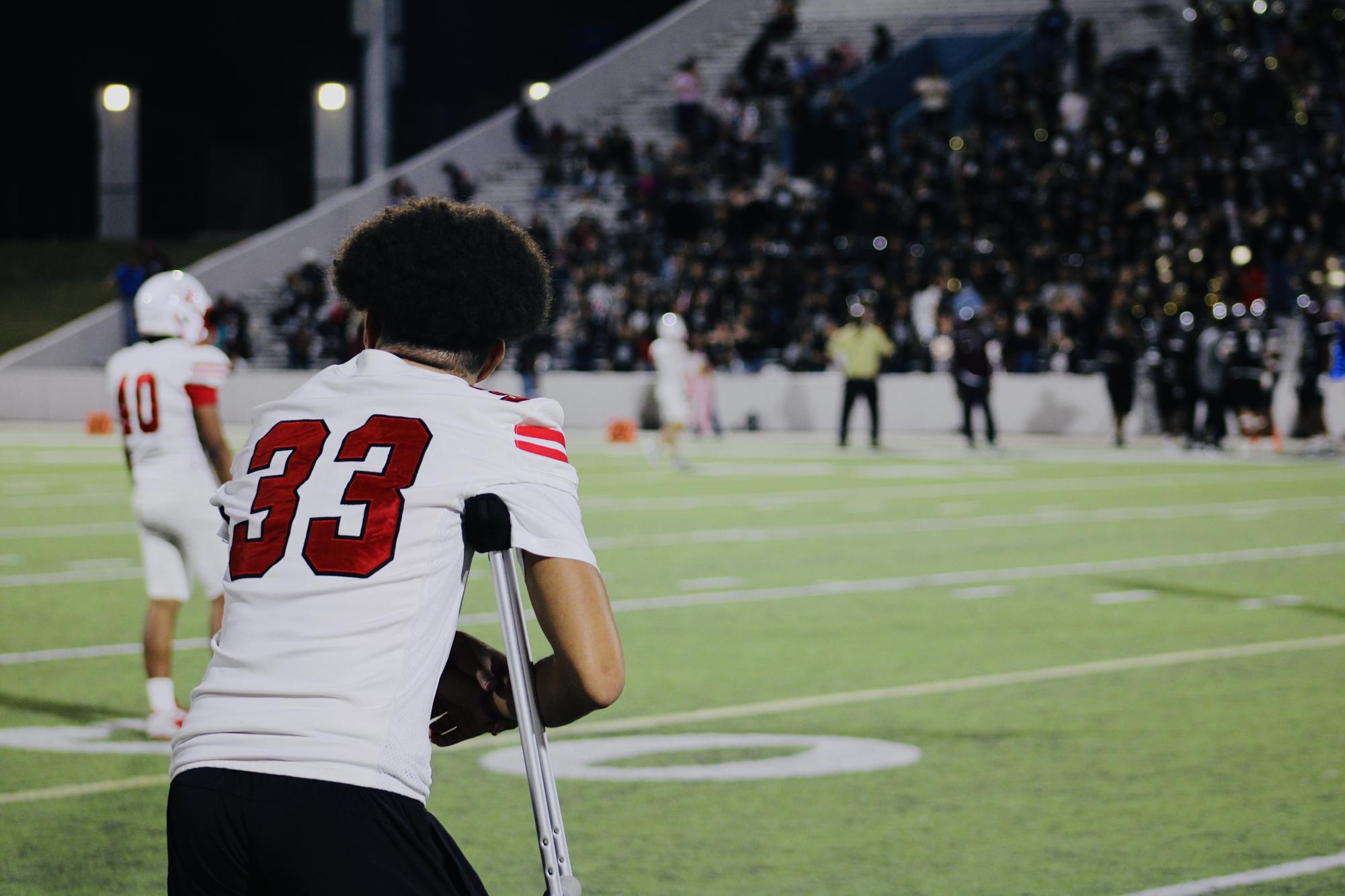 Martinez stands on the sideline during the varsity game against Heights High School on Friday, Oct. 24. He returned to the field weeks after his surgery to continue supporting the team.