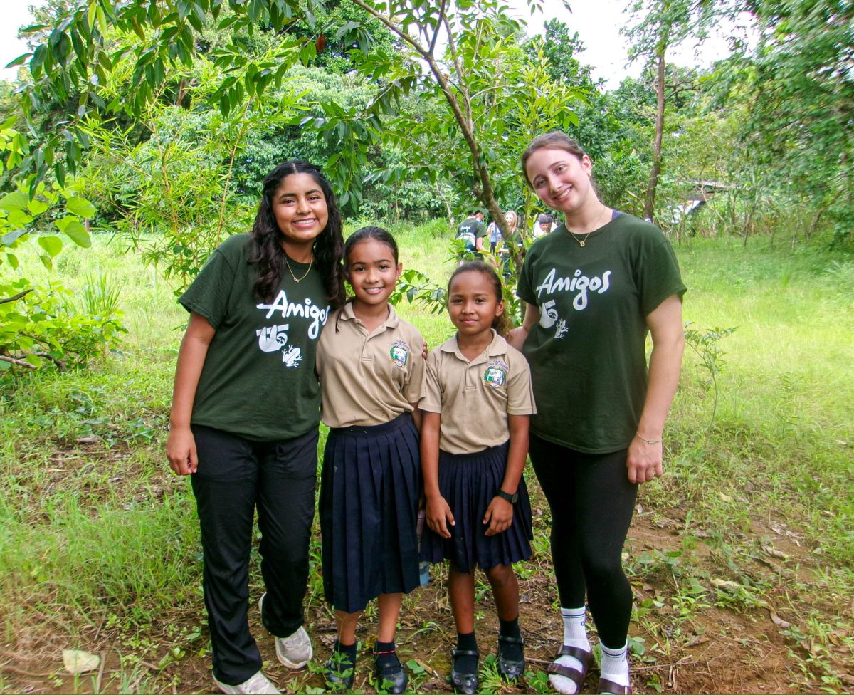 McClain on the right smiles with some of the children in the community. The two girls pictured attended a local school that McClain and other volunteers planted trees at.
