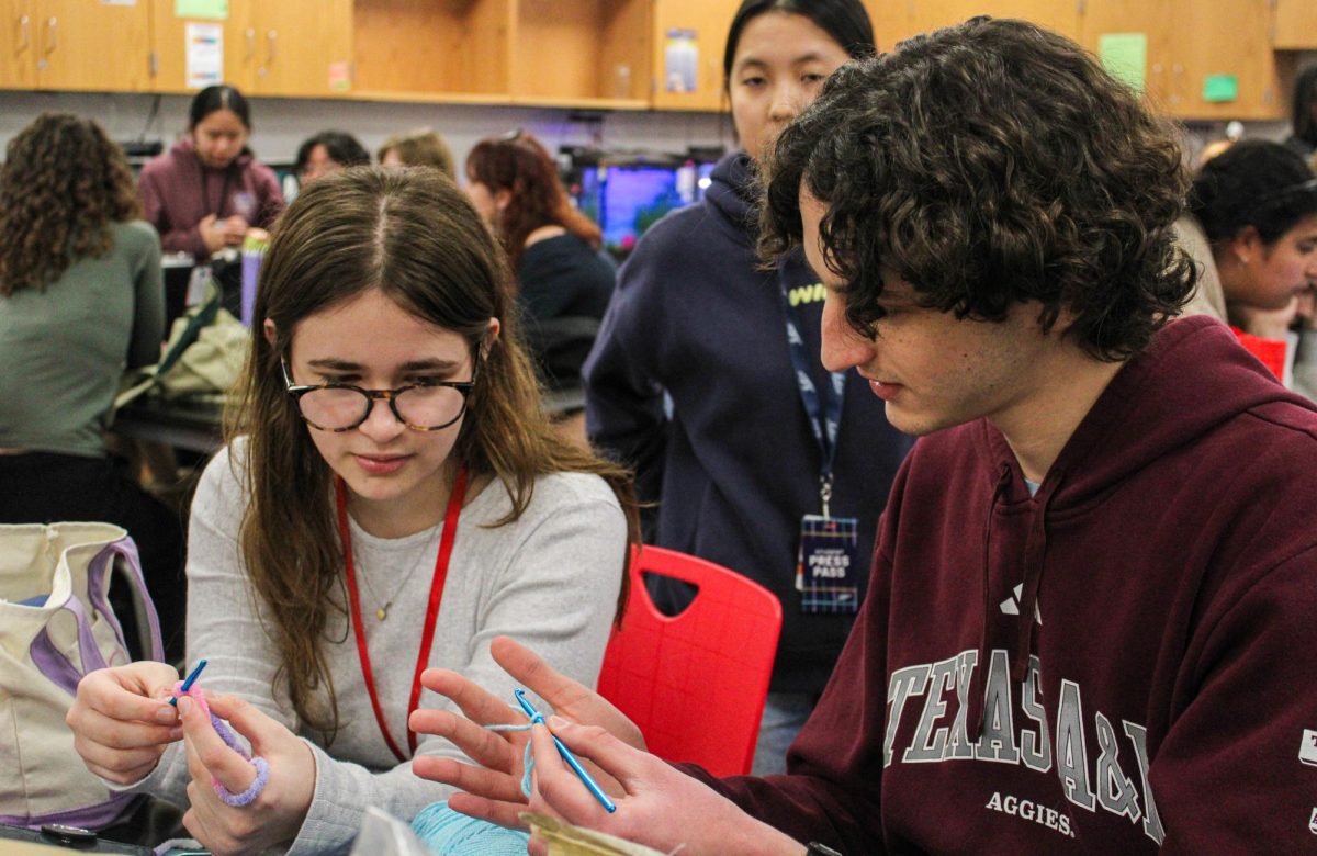 Senior and Co-President Madeleine Luca teaches senior Noah Sullivan how to make a crochet heart. Luca has been co-president since her junior year.
