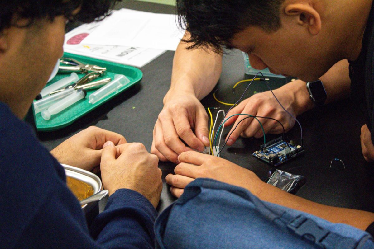 Two Engineering club members build the basic model of their circuit. They applied knowledge from a lesson that discussed the real world implications of lasers, to the hand on activity. 