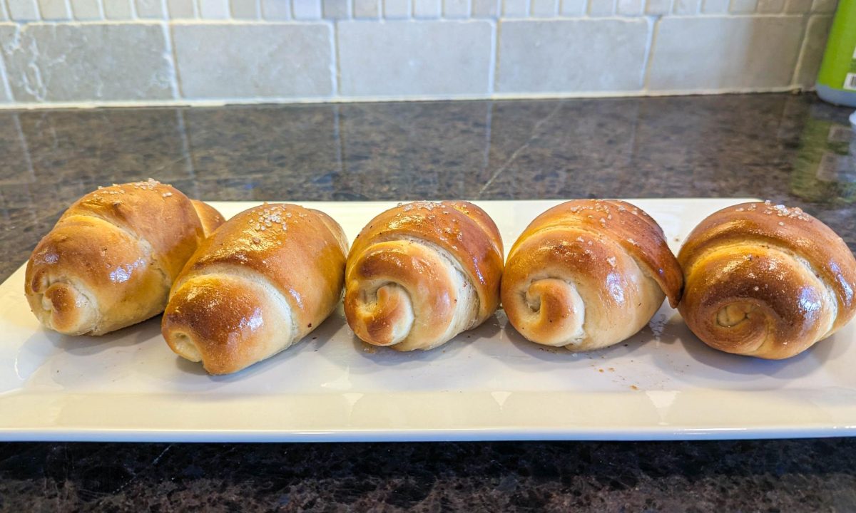 Our batch of salt bread sits on the counter, waiting to be devoured. As a finishing touch, we used a pastry brush to evenly spread melted butter across each surface, giving the bread a garnished look and enhancing its flavor.