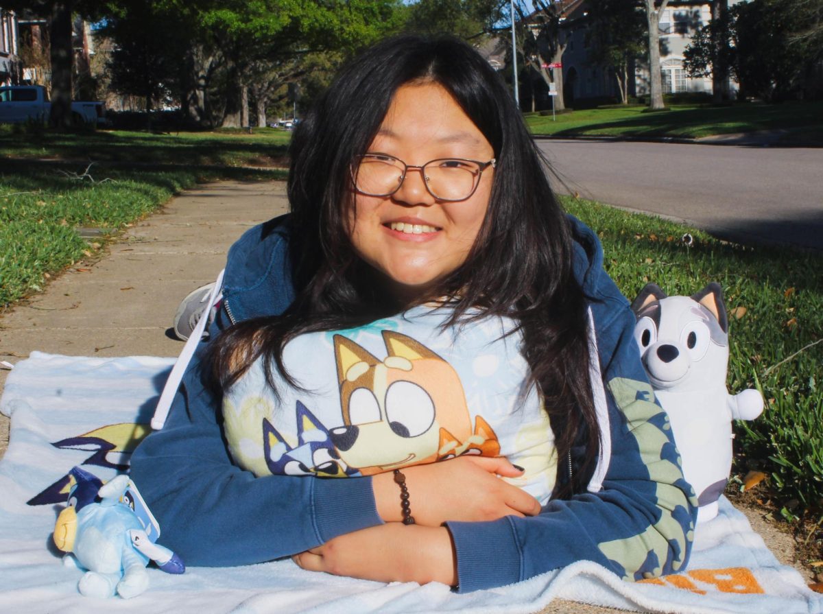 Choi poses with her Bluey plushes and Bluey camera. She has been collecting Bluey merchandise since middle school including Bluey sticker packs, Bluey Christmas pajamas and over five pairs of Bluey socks.