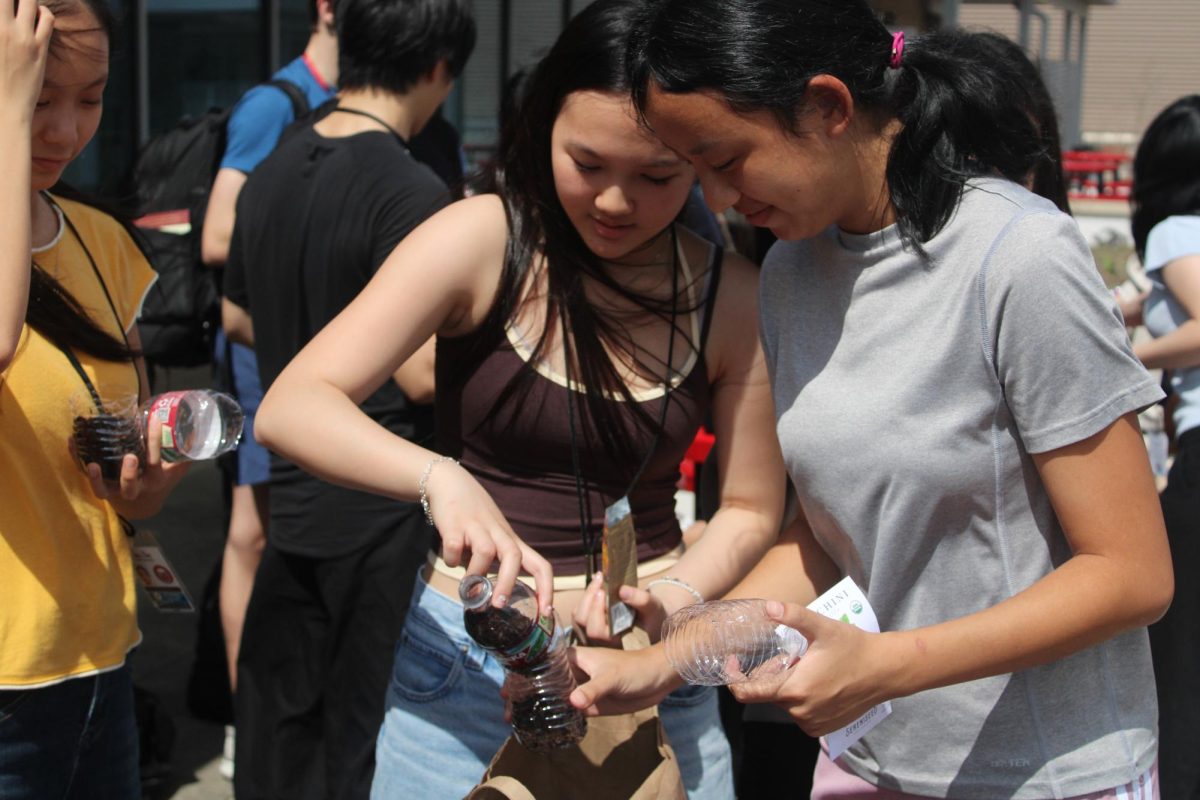 Sophomores Elodie Tran Cao and Laura Du adjust the soil in their bottles. Over 20 water bottles were reused for the activity.