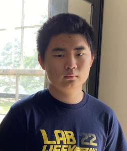 Senior Liyan Feng poses wearing his dad’s Lab Week 22 at Baylor shirt. Both of his parents work in STEM fields, which increased his early exposure to math and sciences.